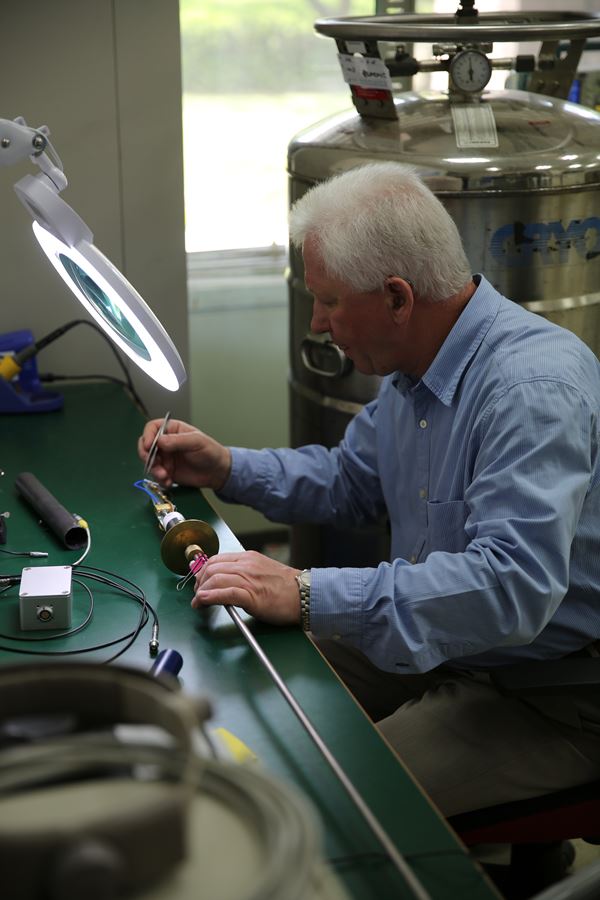 Dr. Matlashov is installing a microstrip SQUID amplifier sample on a cryogenic probe for testing it at 4.2 K inside a liquid Helium transport dewar.